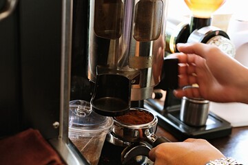 A barista preparing fresh espresso using a professional coffee machine in a café setting.