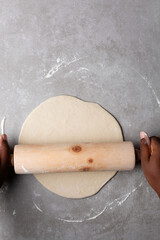 Overhead view of chinese scallion pancake dough being rolled on cement countertop, top view of homemade scallion pancakes, process of making cong you bing