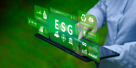 Business professionals are experiencing a digital overlay displaying an ESG framework, renewable energy, and data analytics on a computer screen, against a natural background.