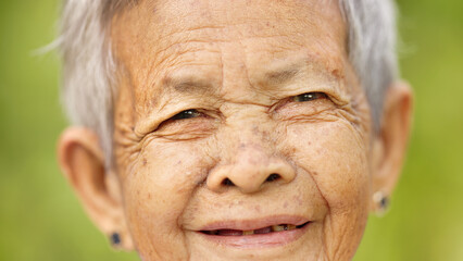 face closeup of smiling old filipino woman with grey hair, wrinkle, and missing teeth, happy senior...
