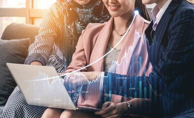 Three business professionals engage in discussion around a laptop, analyzing financial graphs and data, highlighting teamwork and collaborative strategy in a modern setting. Scalp