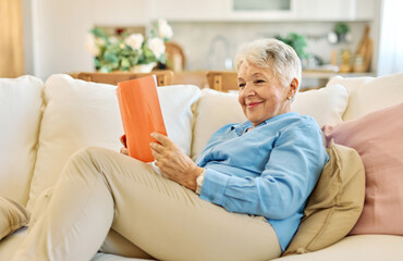 Portrait of mature senior woman reading a book on sofa at home