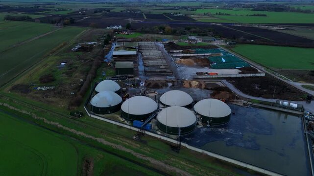 Aerial view of a biogas plant with circular digesters contrasting against the geometric fields and structures, Wisbech, England, United Kingdom.