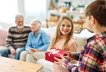 granddaughter and grandson surprises their grandparents with present on mother's day or birthday at home