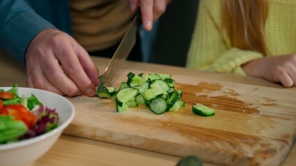 Close up unrecognizable Caucasian family at kitchen cook together man father cutting cucumber...