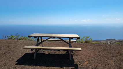 Empty wooden picnic table offering panoramic view of the Atlantic Ocean, Valverde, Island El Hierro, Canary Islands, Spain, Europe. © Iryna Shpulak
