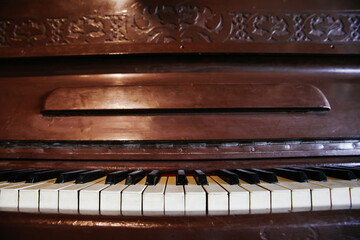 Front-on Close-up of Vintage Upright Piano Keys and the Dark Brown Wood Case with Decorative Carved Details, Evoking Classical Music and History