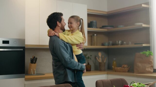 Happy affectionate Caucasian family in kitchen home father man dad with kid daughter cuddling hugging holding child girl talking carefree devotion parenting good fatherhood bonding insurance concept