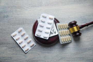 Judge gavel and medical pills on the table.