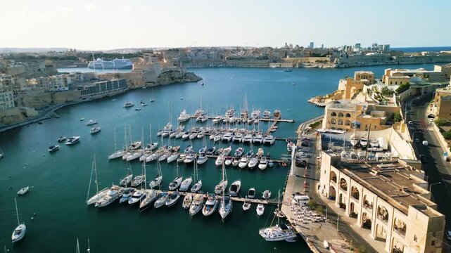 Aerial view of luxury yachts and sailboats in a crowded marina, Malta. Top down drone shot of turquoise Mediterranean water and summer nautical lifestyle.
