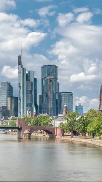 Hyperlapse of Frankfurt's skyscrapers skyline with the bell tower of the Imperial Cathedral of Saint Bartholomew overlooking Alte Brucke, historic stone bridge over the Main River. Frankfurt, Germany