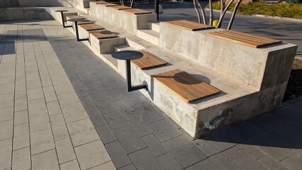 Open Public Space Showcasing Sturdy Concrete Bench With Wooden Slats And Decorative Plantings