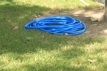 A green garden hose is placed in the garden for watering plants.