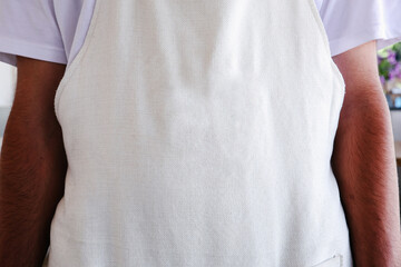 Close-up of the Upper Back Portion of a Blank, Unbleached White Canvas Apron, Highlighting the Fabric Texture and Fit Over a White T-Shirt