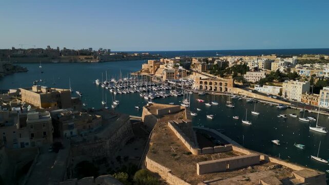 Aerial view of luxury yachts and sailboats in a crowded marina, Malta. Top down drone shot of turquoise Mediterranean water and summer nautical lifestyle.
