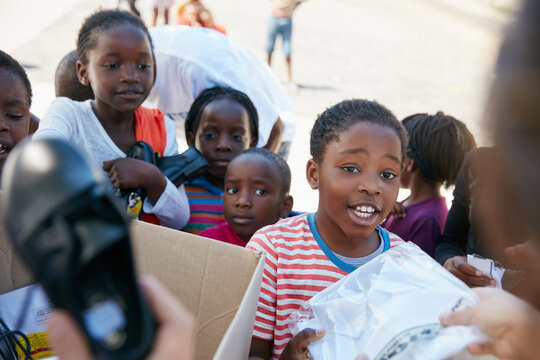 Volunteer, handout and people with donation for children for outreach program, charity event and giving. Team, school and kids with boxes, uniform and parcels for community service, welfare and aid