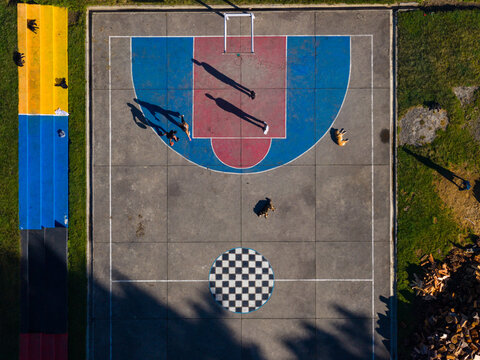 Aerial view of shadows stretching across the vibrant basketball court with its checkerboard pattern and bold colors, Thimphu, Bhutan.