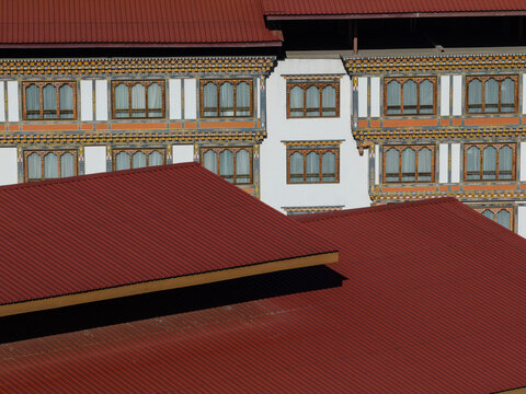 Fototapeta Aerial view of red rooftops contrasting with the white walls and ornate window frames of traditional architecture, Thimphu, Bhutan.