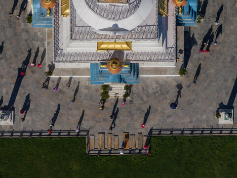 Aerial view of the National Memorial Chorten casts long shadows on the stone courtyard, a bright contrast to the green lawn, Thimphu, Bhutan.