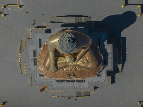 Aerial view of the golden Buddha Dordenma statue casting a long shadow over the stark, paved expanse, a symbol of serenity amidst the urban landscape, Thimphu, Bhutan.