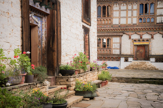 View of flower pots adding vibrant splashes of color against the textured walls of ancient architecture, Ogyencholing, Bumthang, Bhutan.