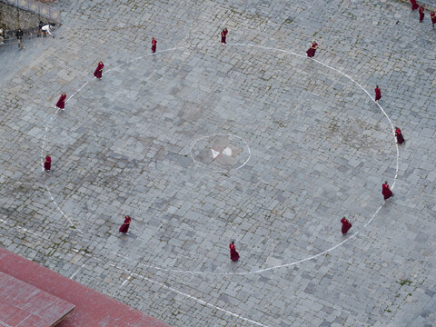 Karpo Lhakhang, Bhutan - 25 September 2025: Aerial view of crimson-robed monks in a circle on the stone courtyard, a stark contrast against the grey stone, creating a mesmerizing spectacle.