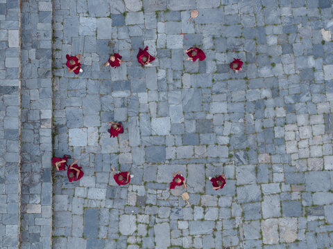 Karpo Lhakhang, Bhutan - 25 September 2025: Aerial view of figures in deep red robes scattered across a textured grey stone plaza, creating a striking contrast in color and tone.