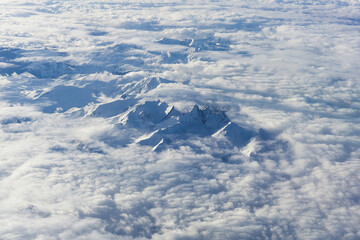 Fototapeta premium Aerial View of Majestic Snow Capped Mountain Summits Rising Above Clouds in Europe