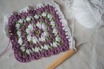 Process of creation of square napkin using Crochet hook and white and lilac yarn