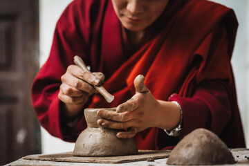 Walakha, Bhutan - 19 September 2025: View of a nun's skillful hands molding clay with a tool, creating intricate details at Sangchhen Dorji Lhuendrup Lhakhang Nunnery.