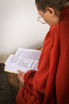 Walakha, Bhutan - 19 September 2025: View of a nun absorbed in sacred texts at Sangchhen Dorji Lhuendrup Lhakhang Nunnery, her red robes a striking contrast against the white walls.