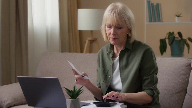 Caucasian old lady senior woman managing personal family budget counting money with receipt check expense with laptop calculator checking financial loan retired female with computer paying online bill