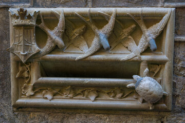 Historic Casa de l Ardiaca mailbox in Barcelona with carved swallows and turtle detail, showcasing iconic architectural symbolism and craftsmanship.