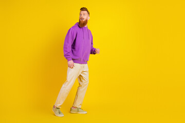 Fototapeta premium Young man with purple hoodie walking against bright yellow background in casual fashion lifestyle photo