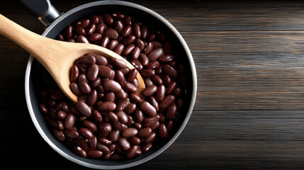 Fototapeta premium Top down view of cooked kidney bean in pot with wooden spoon on dark wood table, healthy protein rich food concept