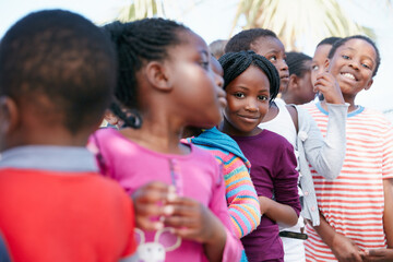 Children, row and smile in portrait at community outreach event, excited or poverty relief at park. African kids, girl and boy in line, happy and group with charity drive, program or humanitarian aid