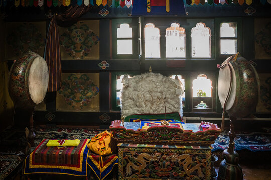Ha, Bhutan - 26 September 2025: View of ornately carved wooden furniture, vibrant textiles, and ancient drums filling a dimly lit interior space with sunlight streaming through the windows.