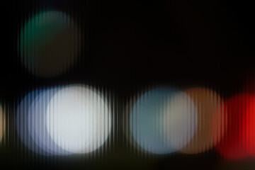 Abstract night car headlights bokeh seen through glass. Dark blue and white blurred light dots texture.
