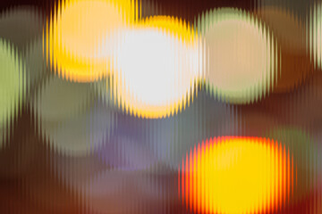 Abstract night city lights seen through ribbed glass. Warm yellow and orange bokeh texture background.