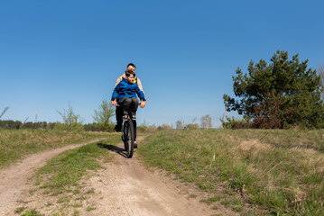Father rides his little son on the handlebars of a bicycle in a meadow