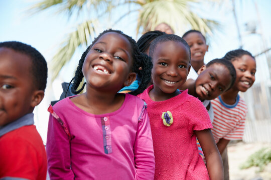 Children, happy and line in portrait at community outreach, excited and poverty relief at park. African kids, girl and boy with smile, row or group at charity drive, society and event at playground