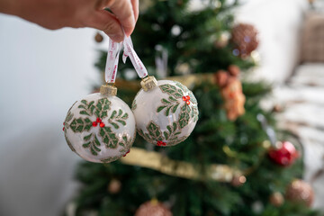 Hands Decorating Christmas Tree With Festive Ornaments At Home