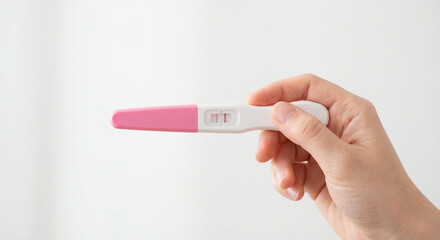 Woman's hand holding a positive pregnancy test stick, revealing exciting news and future plans
