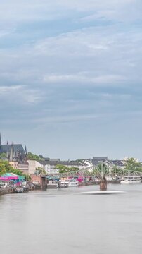 Aerial hyperlapse of pleasure boats on the Rhine Main, framed by the spire of Kaiserdom St. Bartholomaus. Eiserner Steg bridge and Ferris wheel add vibrancy to Frankfurt's scenic waterfront timelapse