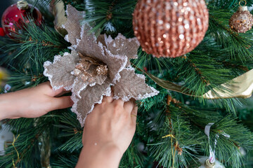 Hands Decorating Christmas Tree With Elegant Golden Flower Ornament