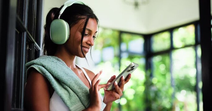 Home, headphones and woman with fitness, cellphone and listening to music, app and subscription. Audio streaming, smartphone and person with radio, exercise or relax with sound and playlist album