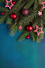  New Year and Christmas background. Fir branch with Christmas decorations on a  dark blue-green painted wooden background.  Flat lay.