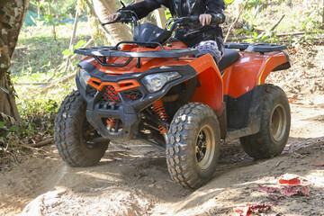 Thrilling outdoor adventure with person driving an orange quad bike on dirt track. This extreme sport offers exciting fun and recreation in natural forest setting © CoreRock