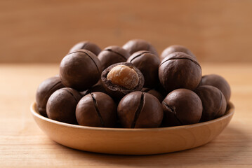 Macadamia nuts in a bowl on wooden background