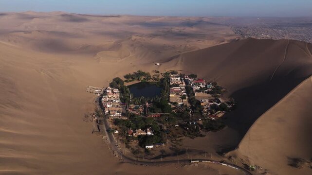 Dense oasis foliage gathers around the lake amid towering dunes shaping the isolated landscape, medium orbit establishing